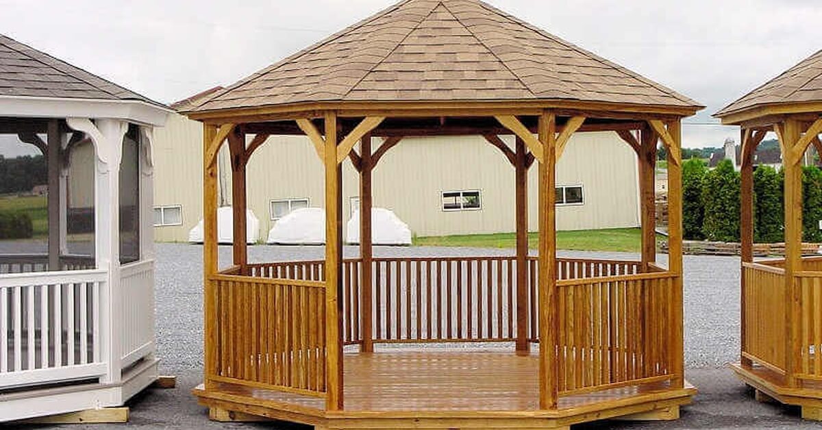 a wooden gazebo with railings, open sides, a shingled roof, and matching structures on both sides near a light building.