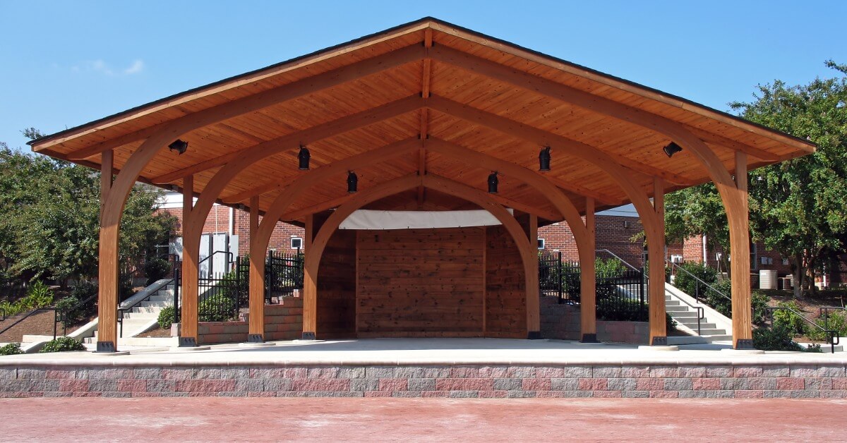 A large wooden pavilion features exposed roof beams and several black light fixtures mounted beneath the roof.